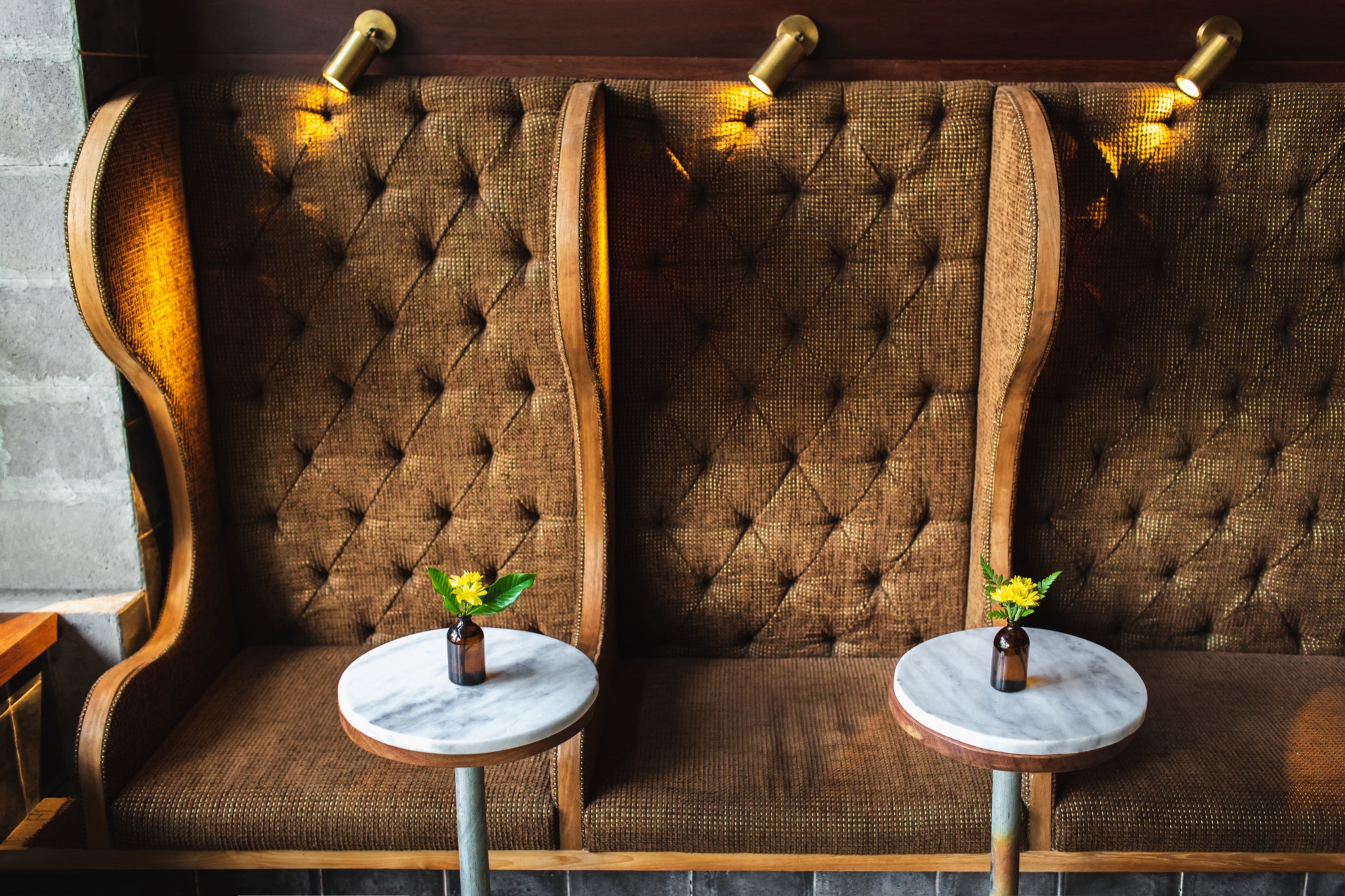 Banquette brune et tables rondes en marbre fleuries dans la salle